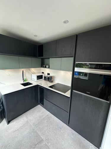 a kitchen with black cabinets and white appliances at Fab-u-Luss in Luss