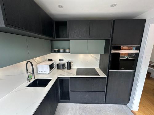 a kitchen with black cabinets and white counter tops at Fab-u-Luss in Luss