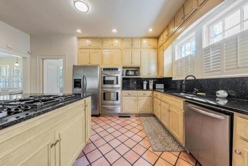 コロンバスにあるGroup Getaway in a Grand Historic Home 15 minutes to Fort Benning Sleeps 10のキッチン(木製キャビネット、ステンレス製の電化製品付)