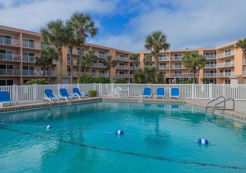 a swimming pool with blue chairs and a building at Newly Renovated St Augustine Beach & Tennis Club 2bed 2bath Condo w Oceanview in Saint Augustine