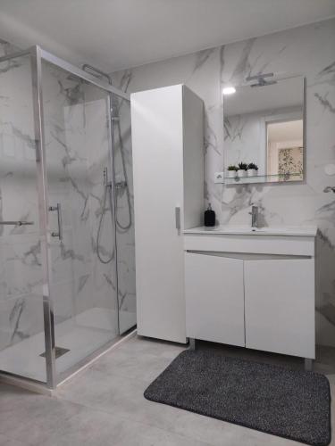 a white bathroom with a shower and a sink at Casa das Olarias in Castelo Branco
