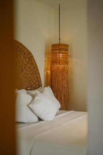 a bed with white pillows and a chandelier at Evoé Caraíva in Caraíva
