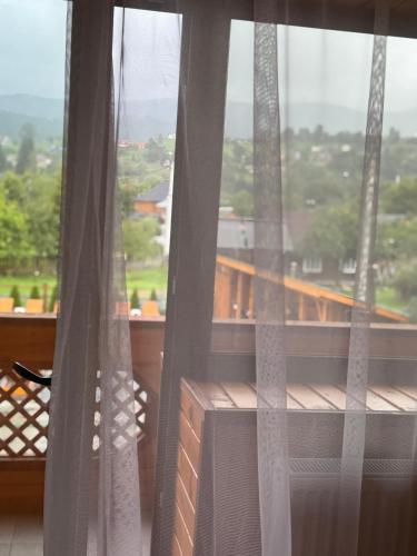 a window with curtains and a view of a balcony at Готель TWINS РАЙ in Vorokhta