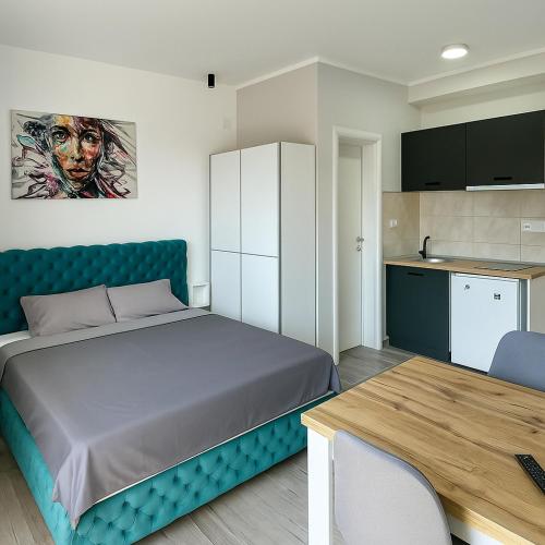 a bedroom with a bed and a table and a kitchen at Apartmani borova 2 in Veliko Gradište