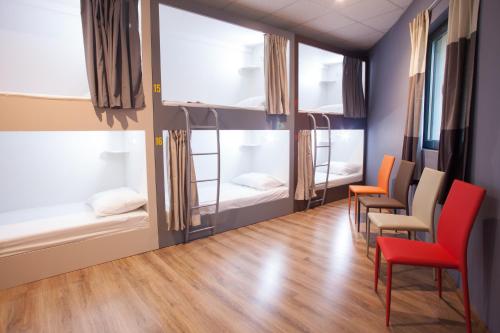 スプリトにあるEn Route Hostelの二段ベッド、椅子、テーブルが備わる客室です。