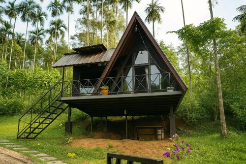 a small house with a staircase in the grass at Wetlands Wayanad Pool Resort with Natural Waterfalls in Padinjarathara
