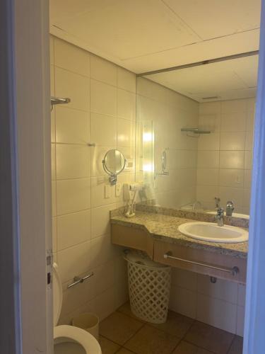 a bathroom with a sink and a toilet and a mirror at Flat frente à praia !! Boqueirão Santos! in Santos