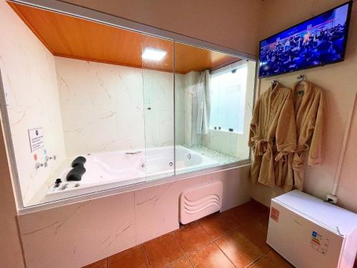 a bathroom with a large tub with a window at Pousada Vison Ubatuba - Praia Grande in Ubatuba
