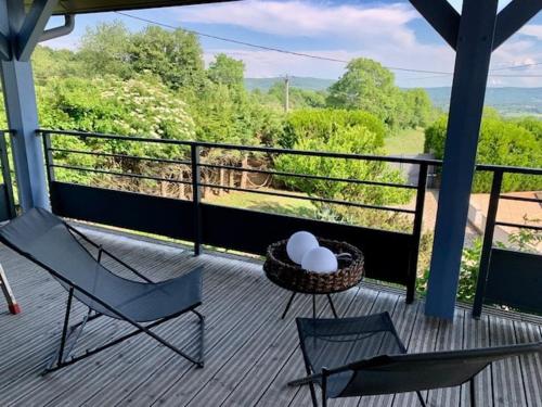 two chairs and a table on a porch with a view at Maison verdoyante et piscine in Abbans-Dessus