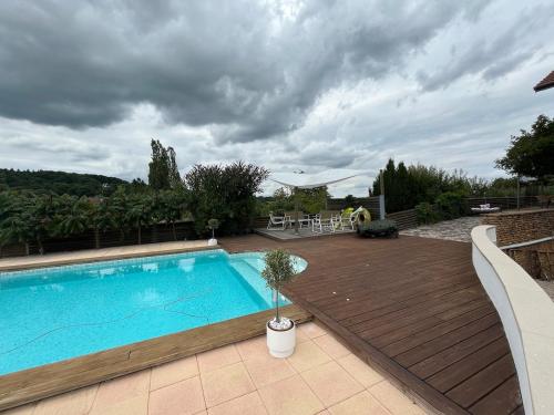 a swimming pool with a wooden deck at Maison verdoyante et piscine in Abbans-Dessus