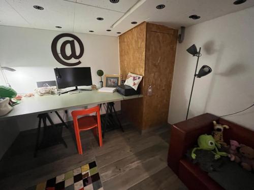 a room with a desk with a computer and a couch at Maison verdoyante et piscine in Abbans-Dessus