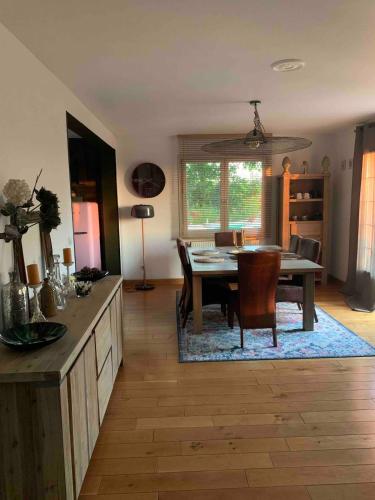 a living room with a table and a dining room at Maison verdoyante et piscine in Abbans-Dessus