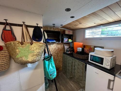 a caravan with bags hanging on the wall and a microwave at Maison verdoyante et piscine in Abbans-Dessus