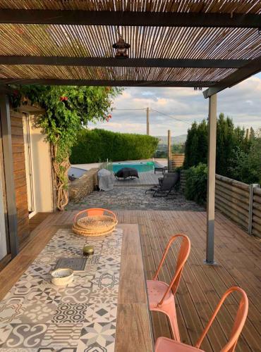 a patio with a table and chairs on a deck at Maison verdoyante et piscine in Abbans-Dessus