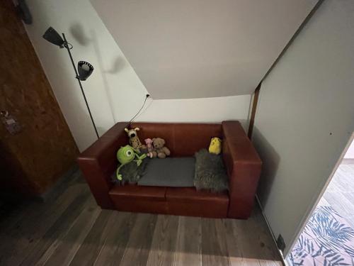 a brown couch with stuffed animals sitting on it at Maison verdoyante et piscine in Abbans-Dessus