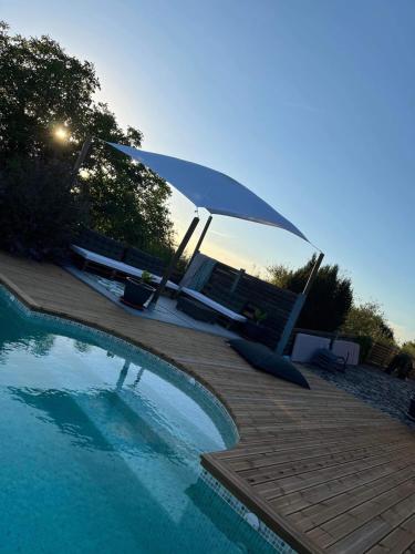 a swimming pool with an umbrella and some chairs at Maison verdoyante et piscine in Abbans-Dessus
