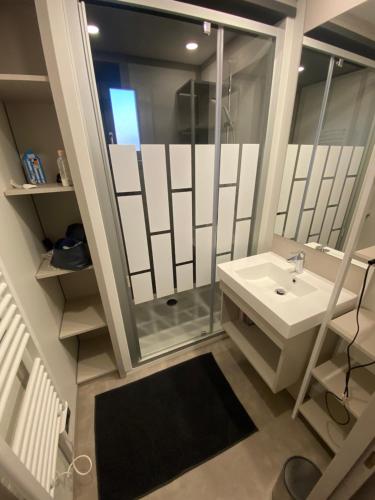 a white bathroom with a sink and a shower at chalet de l'Edune 6 pers beau standing piscine couverte à 150m de la mer wifi inclus in Jullouville-les-Pins