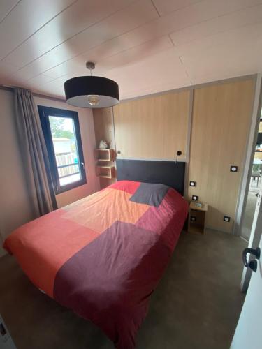 a bedroom with a bed with a colorful blanket at chalet de l'Edune 6 pers beau standing piscine couverte à 150m de la mer wifi inclus in Jullouville-les-Pins