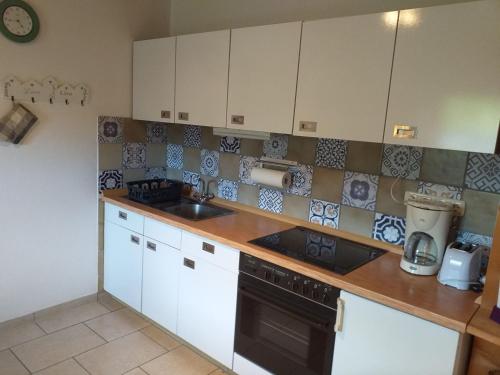 a kitchen with white cabinets and a black stove top oven at Fewo Steinbeisser in Arrach