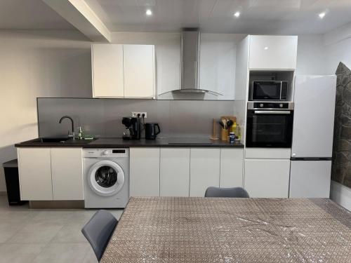 a kitchen with white cabinets and a washing machine at Bas de villa à découvrir in Rivière-Pilote