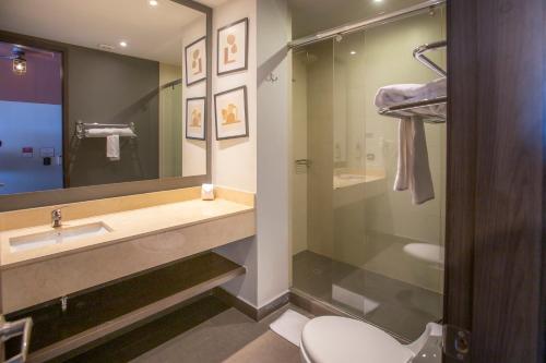 a bathroom with a sink and a toilet and a mirror at Socialtel Parque 93 Bogota in Bogotá