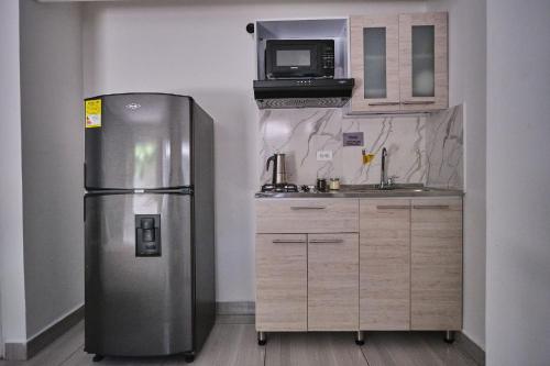 a kitchen with a stainless steel refrigerator and a microwave at Apartahotel Poblado-Aguacatala in Envigado