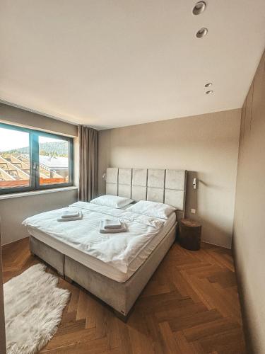 a bedroom with a large bed and a large window at Apartmán MONTARA in Donovaly
