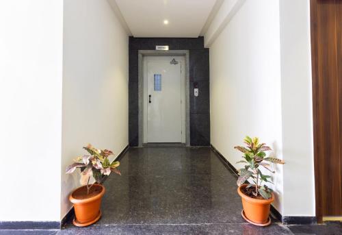 a hallway with two potted plants in front of a door at Hotel O Qualia Inn Kondapur Near Botanical Garden in Hyderabad