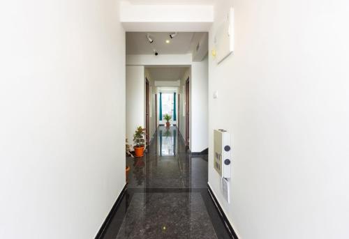 a hallway with white walls and black flooring at Hotel O Qualia Inn Kondapur Near Botanical Garden in Hyderabad