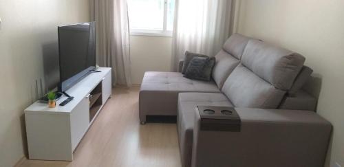 a living room with a couch and a flat screen tv at Ap aconchegante perto de tudo in Caxias do Sul