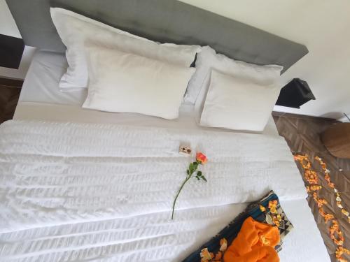 a white bed with a red flower on it at Hostal & Spa Casa Real in Baños
