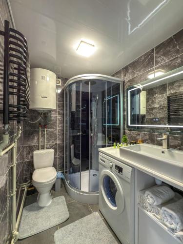 a bathroom with a toilet a sink and a washing machine at Садиба "Ековид" in Krivorovnya
