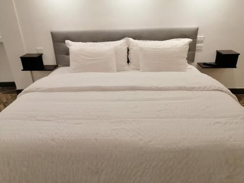 a white bed with white sheets and pillows at Hostal & Spa Casa Real in Baños