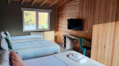 a bedroom with two beds and a flat screen tv at Hostería Las Cumbres in Villa La Angostura