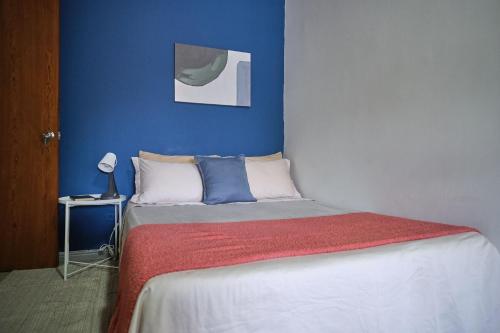 a bedroom with a bed with a blue wall at Apartahotel Poblado-Aguacatala in Envigado