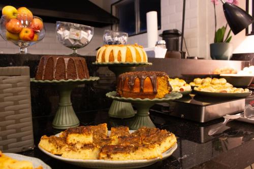 a buffet with cakes and other desserts on plates at Hotel Rosim in Pirassununga