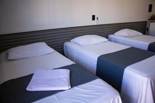 three beds are lined up in a room at Hotel Rosim in Pirassununga