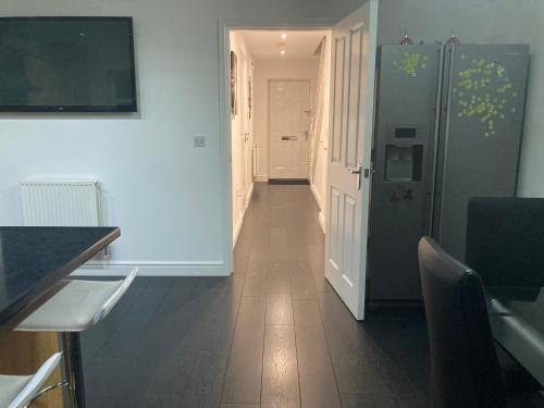 a kitchen with a hallway with a refrigerator and a table at Entire 3 bedroom deluxe house in Cleckheaton