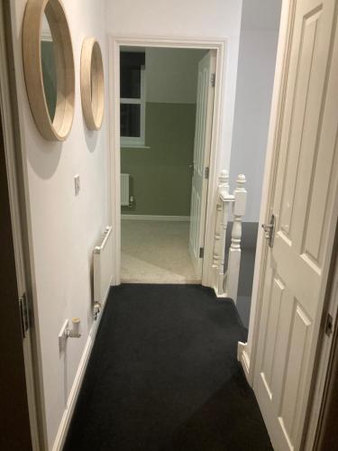 a hallway with an open door and a mirror at Entire 3 bedroom deluxe house in Cleckheaton