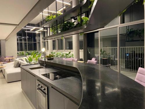 a kitchen with a counter with a sink and a living room at Uma delícia de Ap para SP! in Sao Paulo