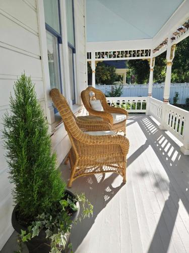 two wicker chairs on the porch of a house at The Queen On Main in Winters