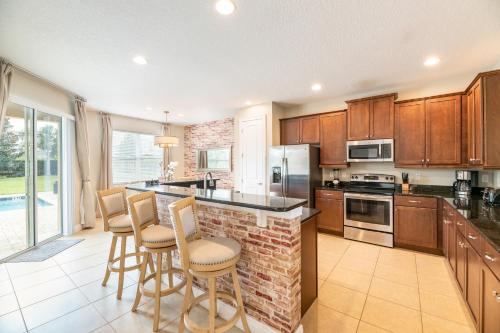a kitchen with wooden cabinets and a bar with stools at Gorgeous Home With Media, Disney Themed Kids Room Near Disney With Waterpark & Resort Access At Encore Resort - 771La in Kissimmee
