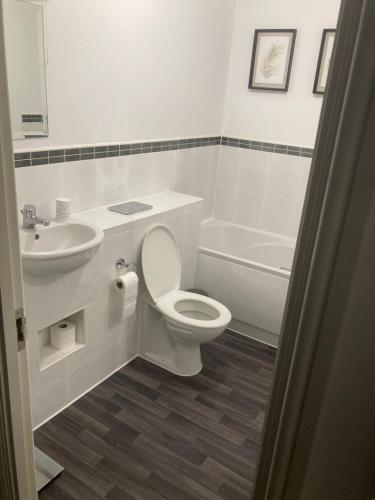 a white bathroom with a toilet and a sink at Entire 3 bedroom deluxe house in Cleckheaton