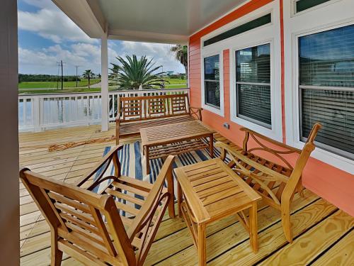 a porch with two wooden chairs and a table at West Bay Getaway in Galveston