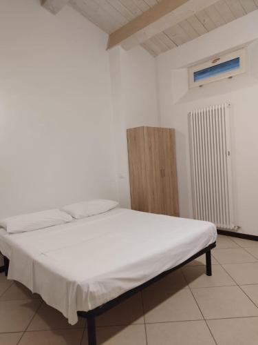 a bedroom with a white bed and a wooden cabinet at Le Torri Lodge, exclusive comfort in the center in Forlì
