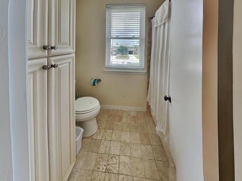 a bathroom with a toilet and a window at West Bay Getaway in Galveston
