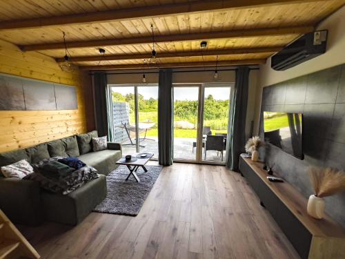 Una sala de estar con un sofá y un televisor. en Domki Kwiatowe N05 - Łeba - Nowęcin, en Nowęcin