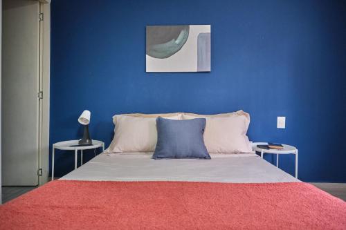 a blue bedroom with a bed with a red blanket at Apartahotel Poblado-Aguacatala in Envigado