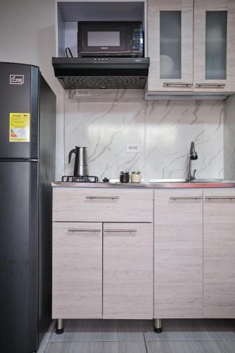 a kitchen with a refrigerator and a microwave at Apartahotel Poblado-Aguacatala in Envigado