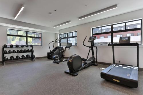 a gym with treadmills and ellipticals in a room with windows at Studio At The Crescent Sleeps 2 to 4 in Rossland